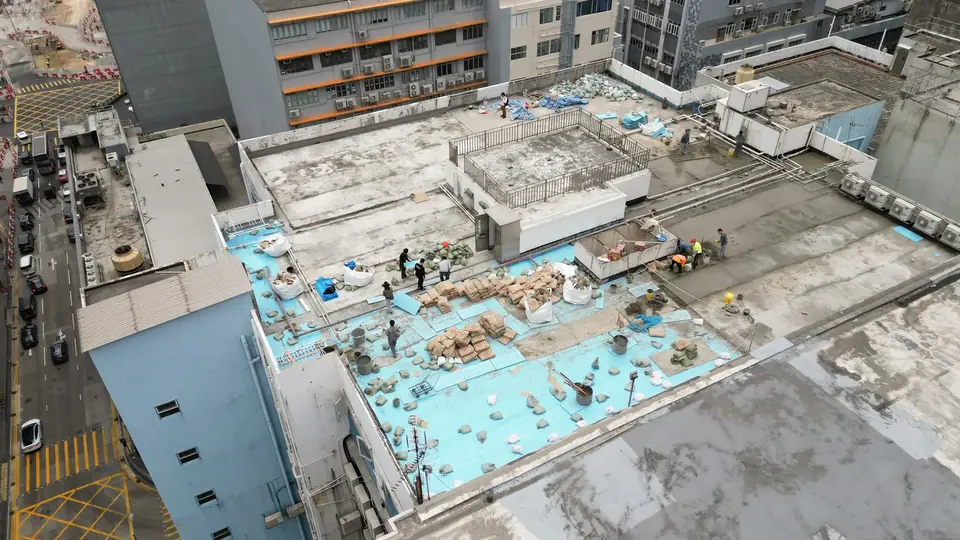 觀塘鴻運工業大廈工程：外露藍色底層、拆除物料及工人的天台航拍