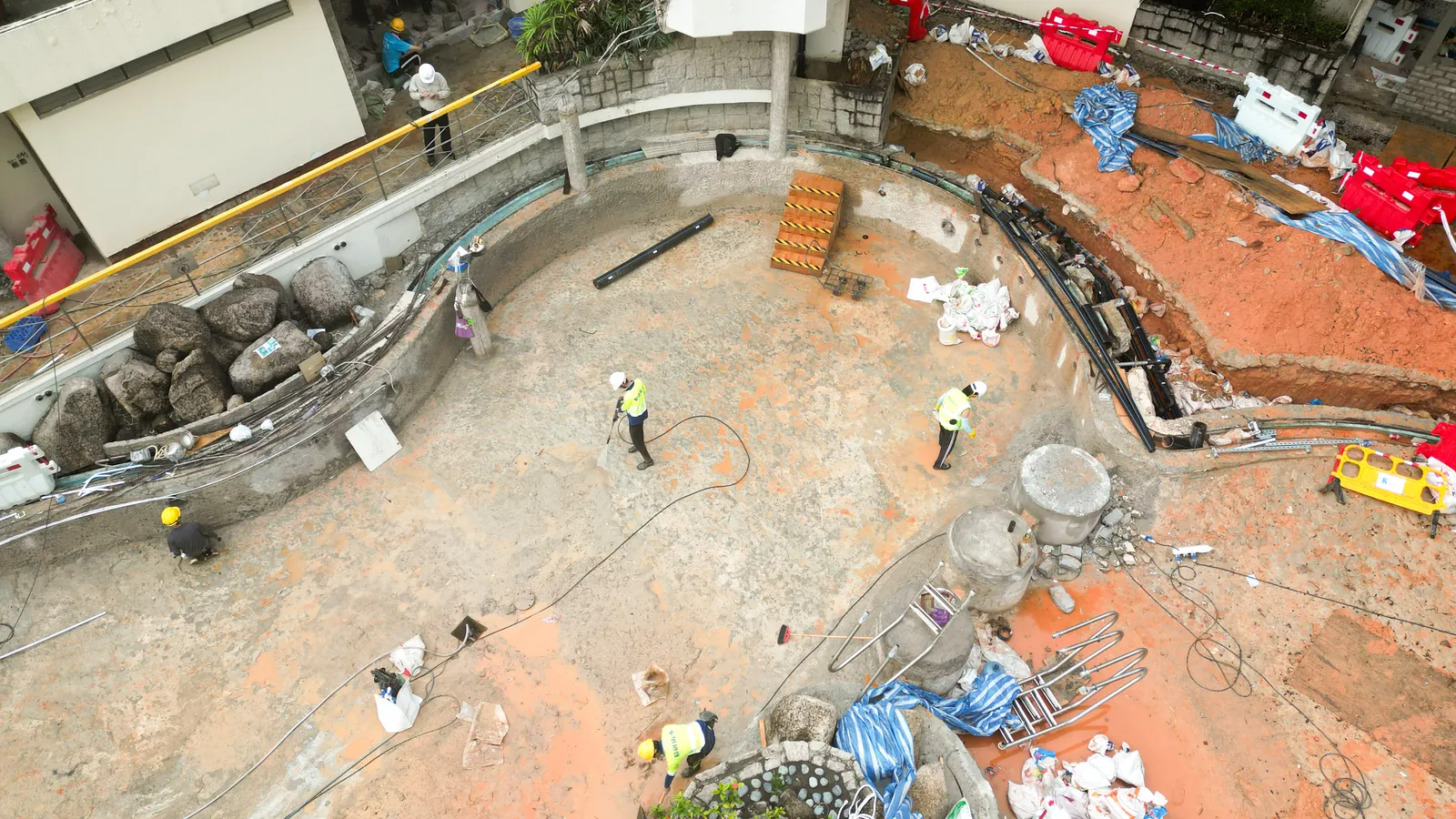 上水雙魚河賽馬會鄉村會所泳池工地俯視圖，可見工人、施工管線及物資