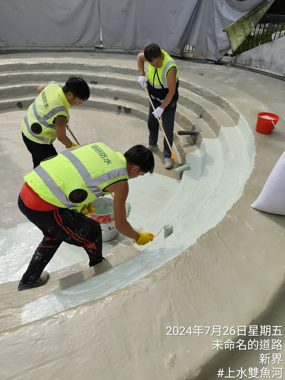 上水雙魚河賽馬會鄉村會所泳池內，三名工人以刷具處理弧形台階表面