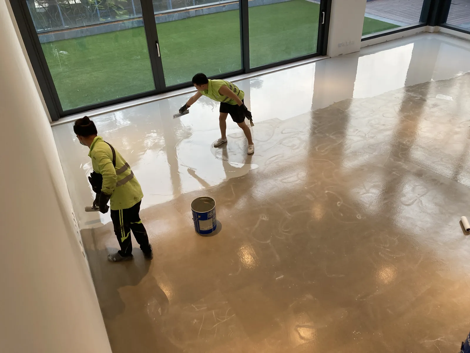 屯門瑧譽住宅樓內俯視圖,兩名工人正在落地玻璃門旁處理反光地面