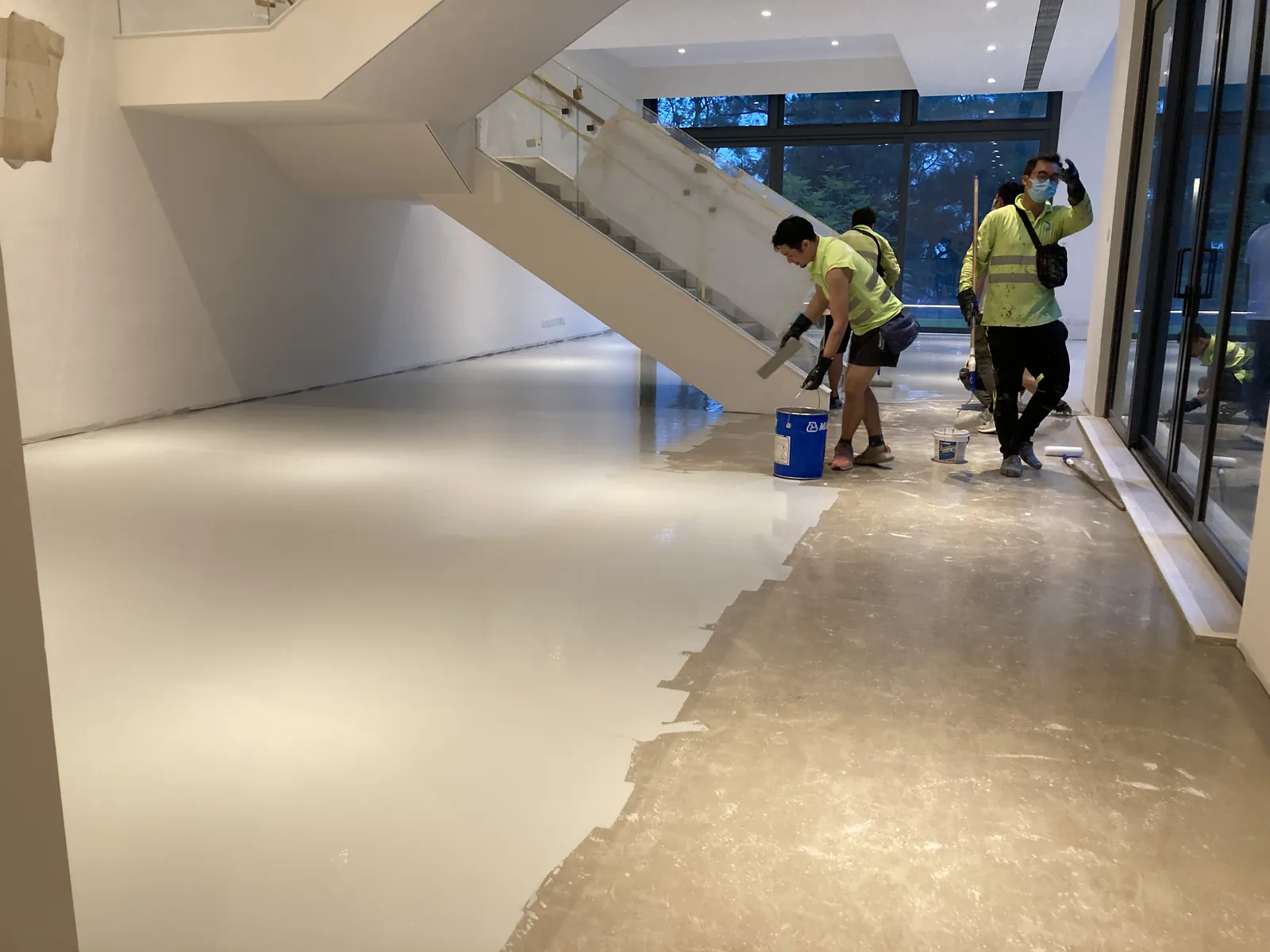 屯門瑧譽住宅樓梯下方,多名工人在淺色地面與外露基面交界處施工