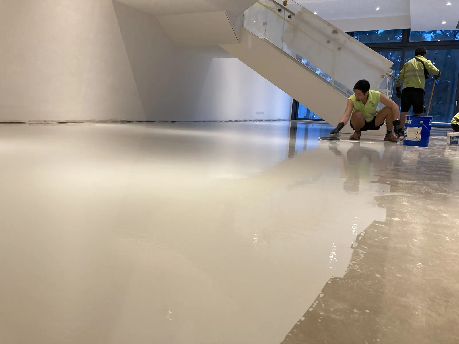 屯門瑧譽住宅樓內低角度視圖,淺色地面延伸至樓梯旁的施工人員