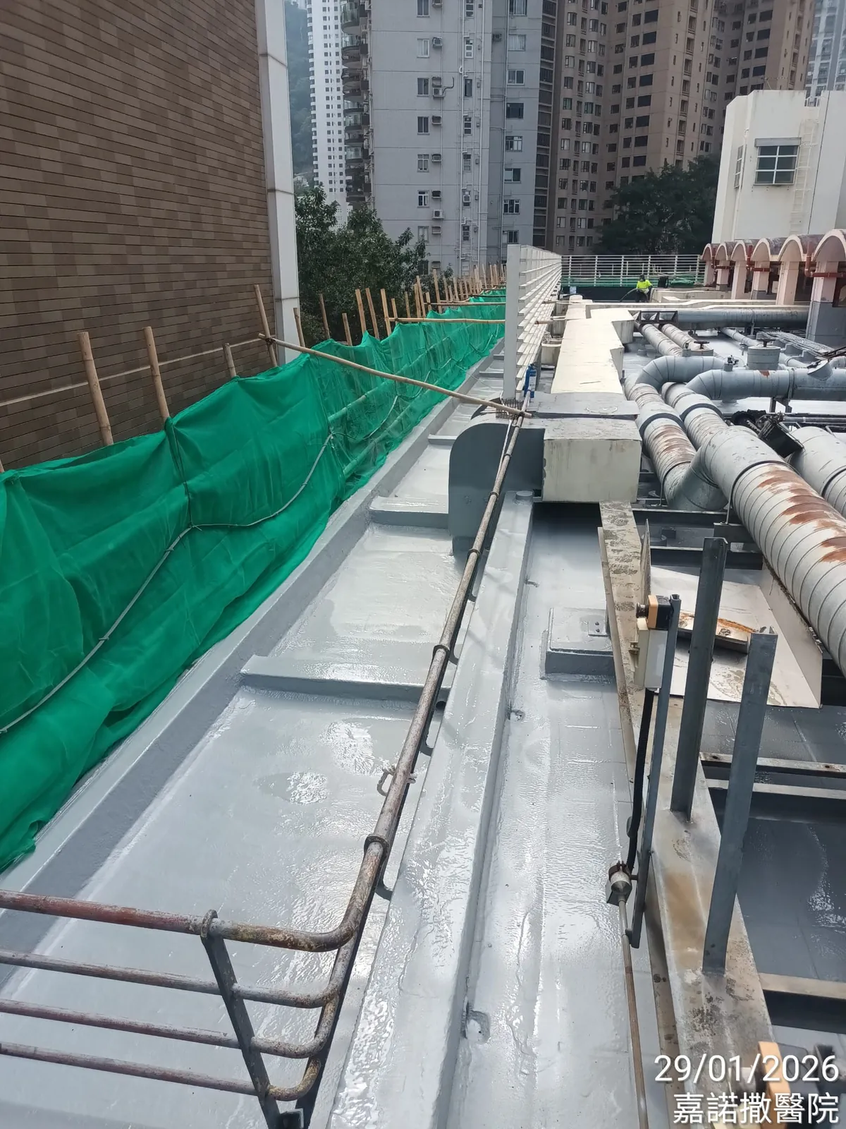 山頂嘉諾撒醫院天台的長形灰色通道，旁邊可見管道及綠色安全網