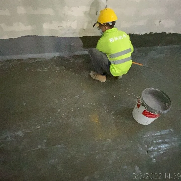 國泰貨運中心工人蹲在牆地接縫旁處理深色牆腳帶，旁邊放有水桶