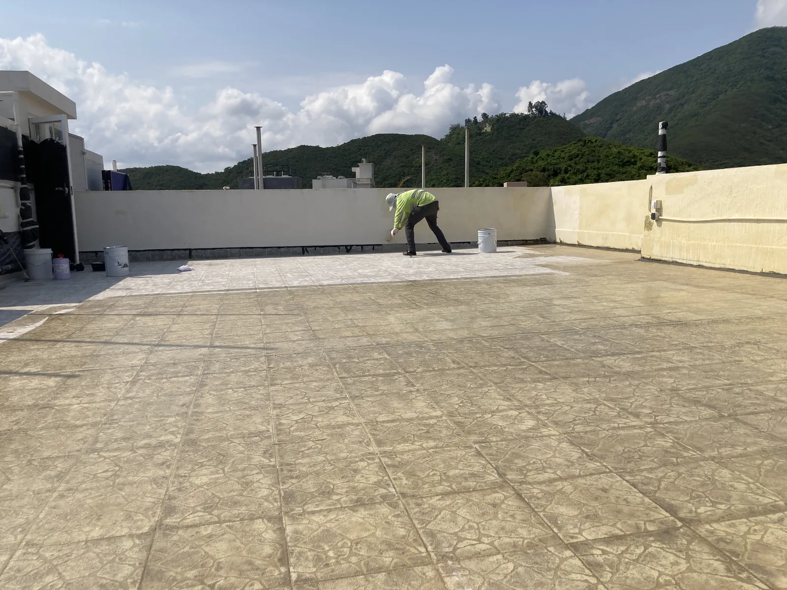Worker applying a light-coloured section across the large patterned rooftop at Bauhinia Gardens