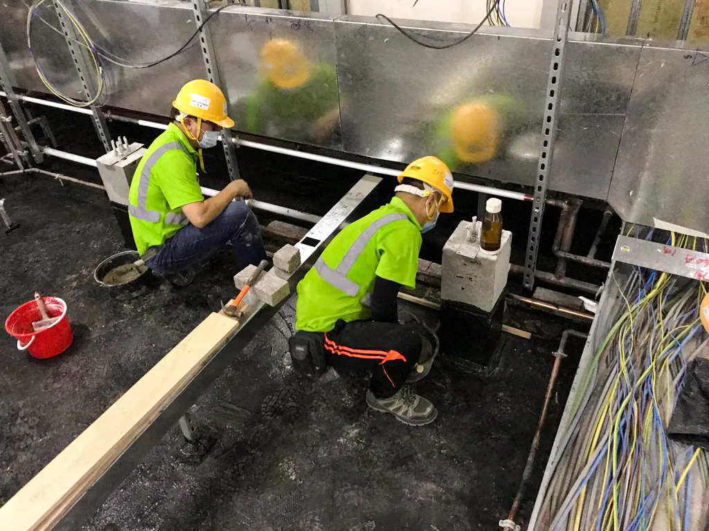 中環匯豐銀行總行內，兩名工人在設備及電纜束旁跪地施工