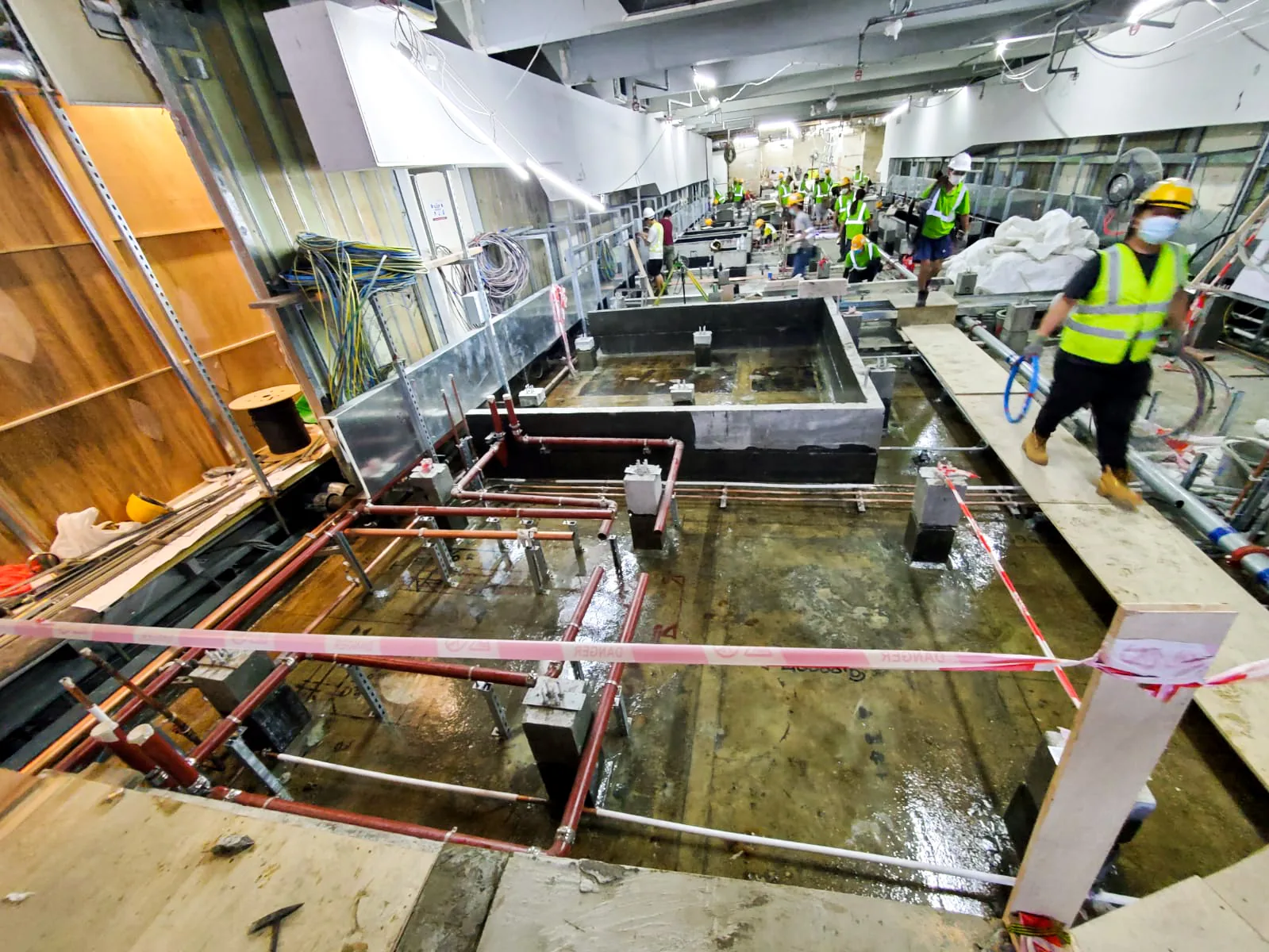 中環匯豐銀行總行樓內工程區全景，可見管道、圍欄及地面施工人員