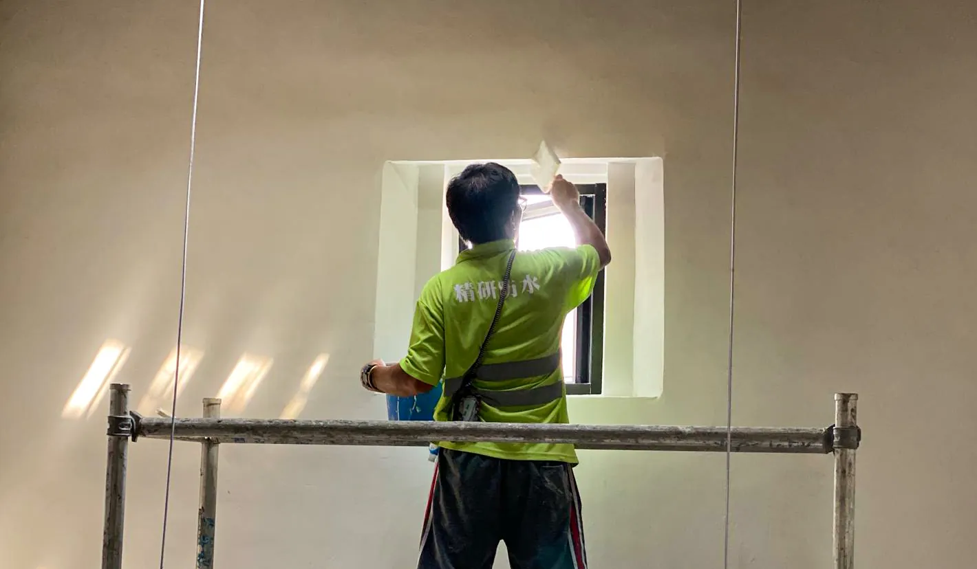 Worker on a platform treating the perimeter of a small interior window at Law Uk Historic House