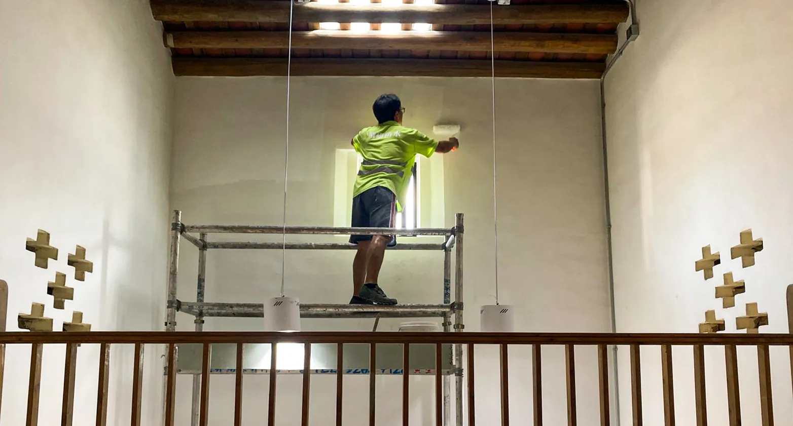 Interior of Law Uk Historic House with exposed timber roof beams and a worker beside a window opening