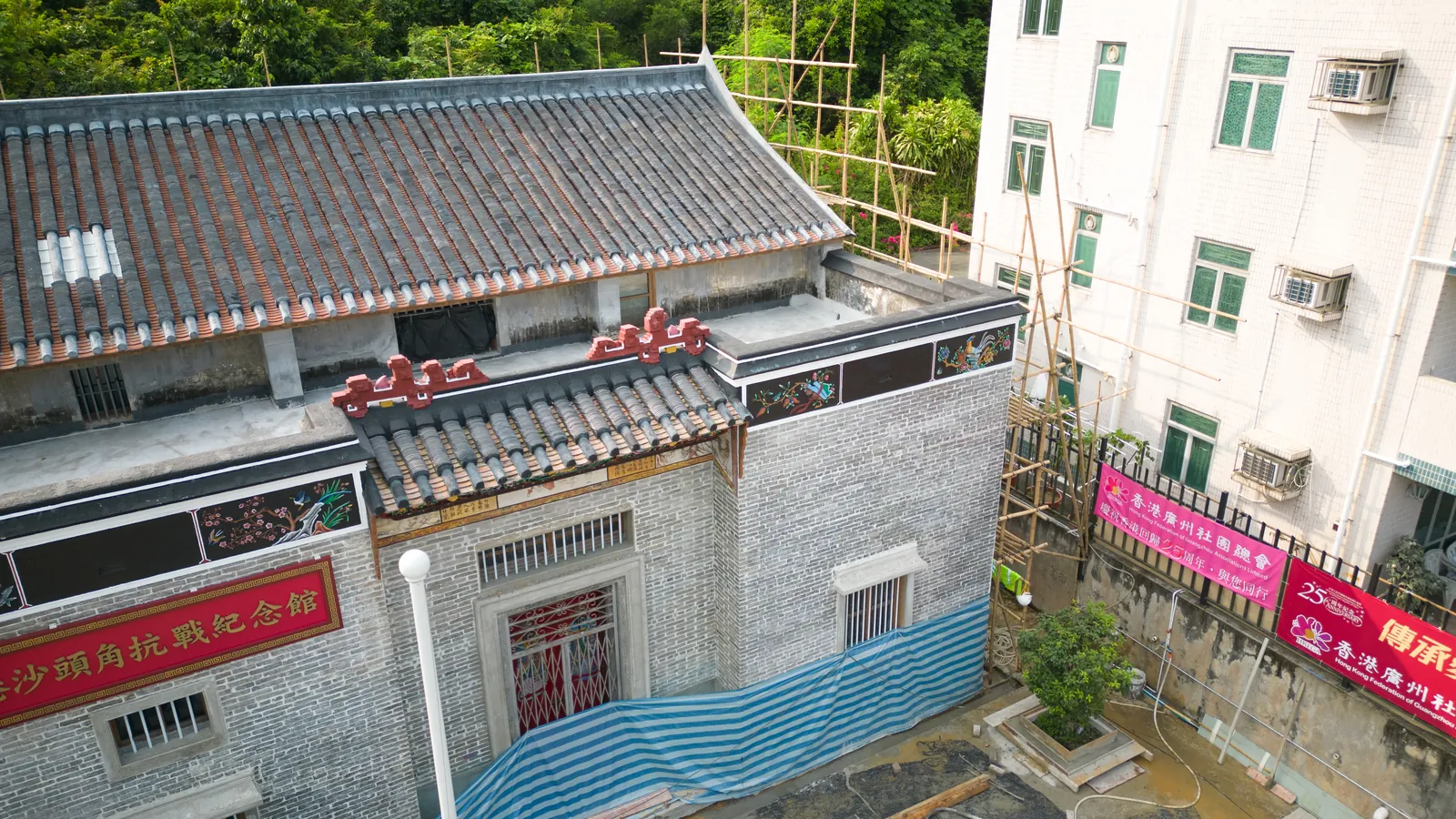 Oblique aerial view of Law Uk Historic House showing grey brick walls, tiled roofs and adjacent scaffolding