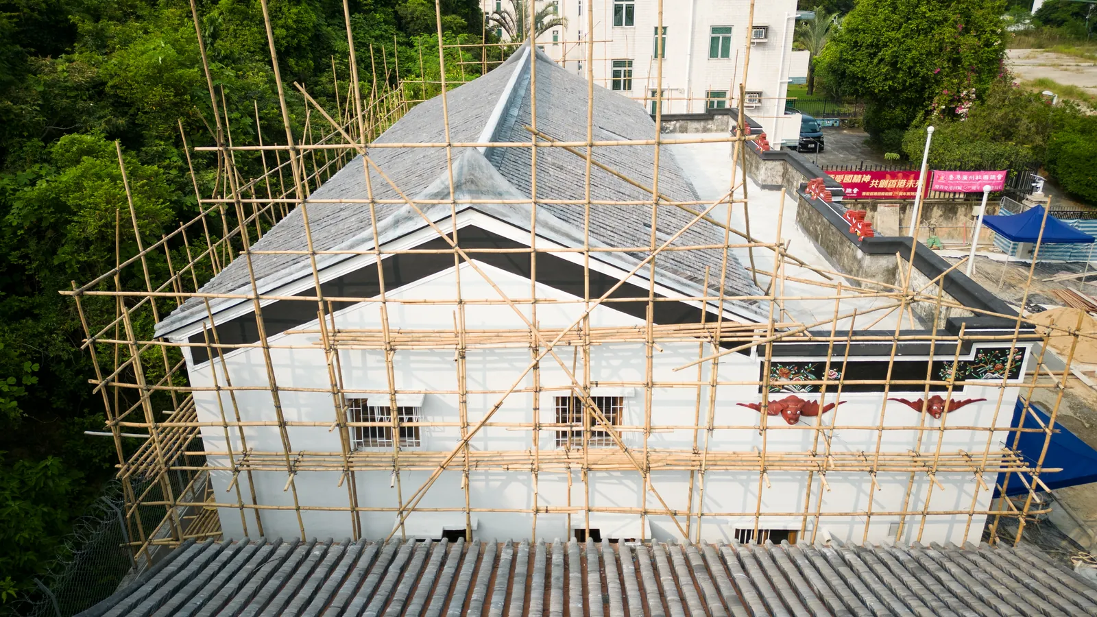 Aerial rear view of Law Uk Historic House showing white walls, pitched tiled roofs and bamboo scaffolding