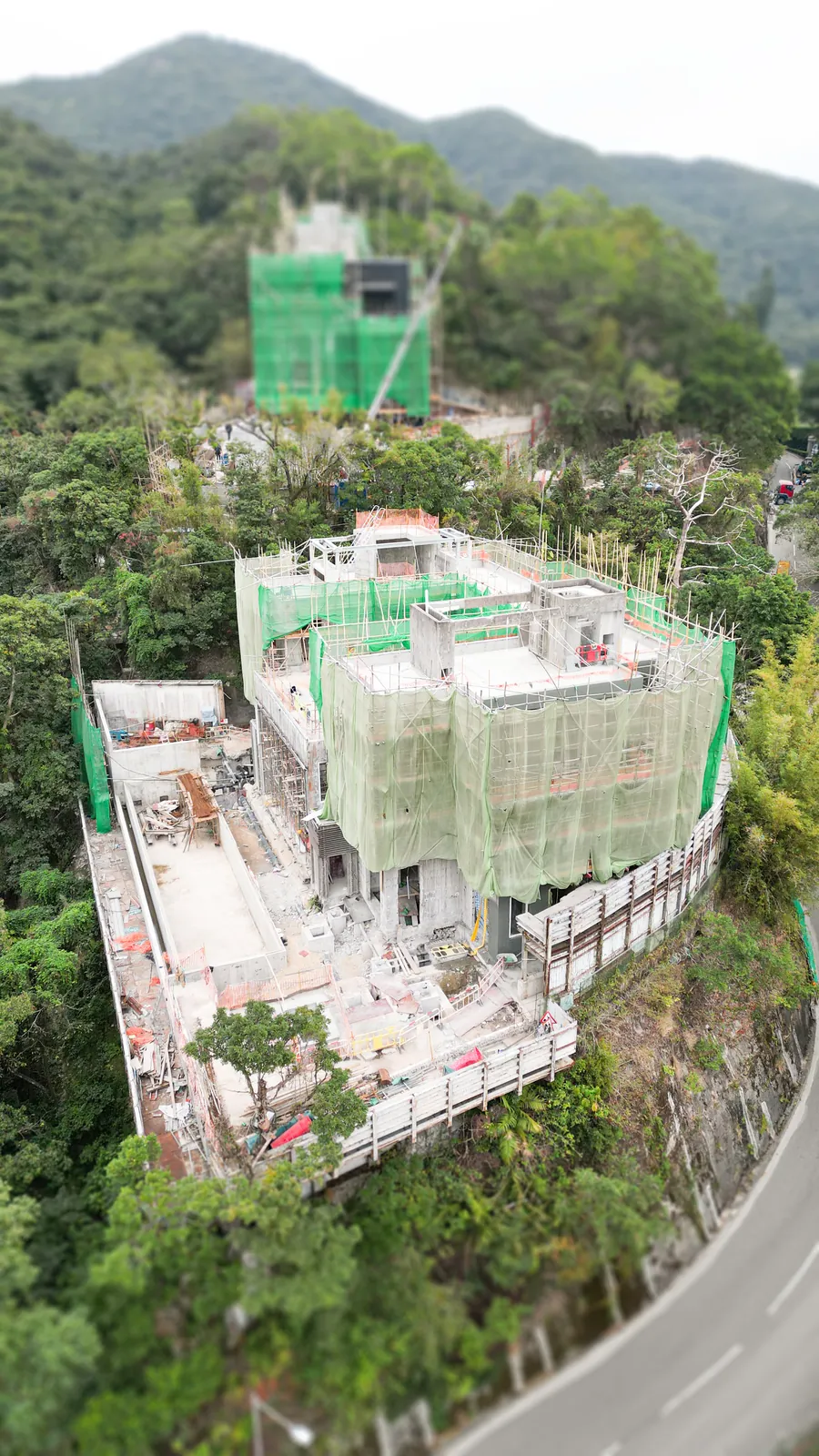 Aerial view of the residential site at No. 3 Middle Gap Road, with green scaffold netting and surrounding woodland