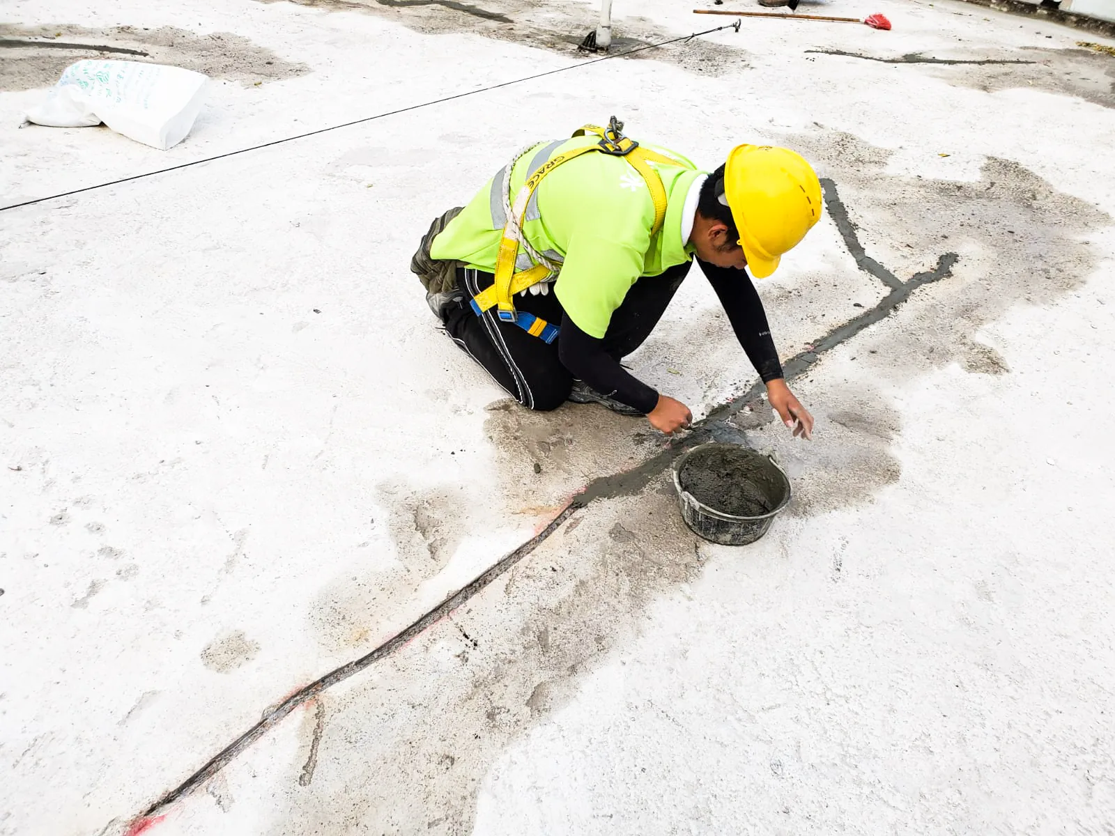 香港加油站工人跪在白色屋面的一道灰色槽位旁