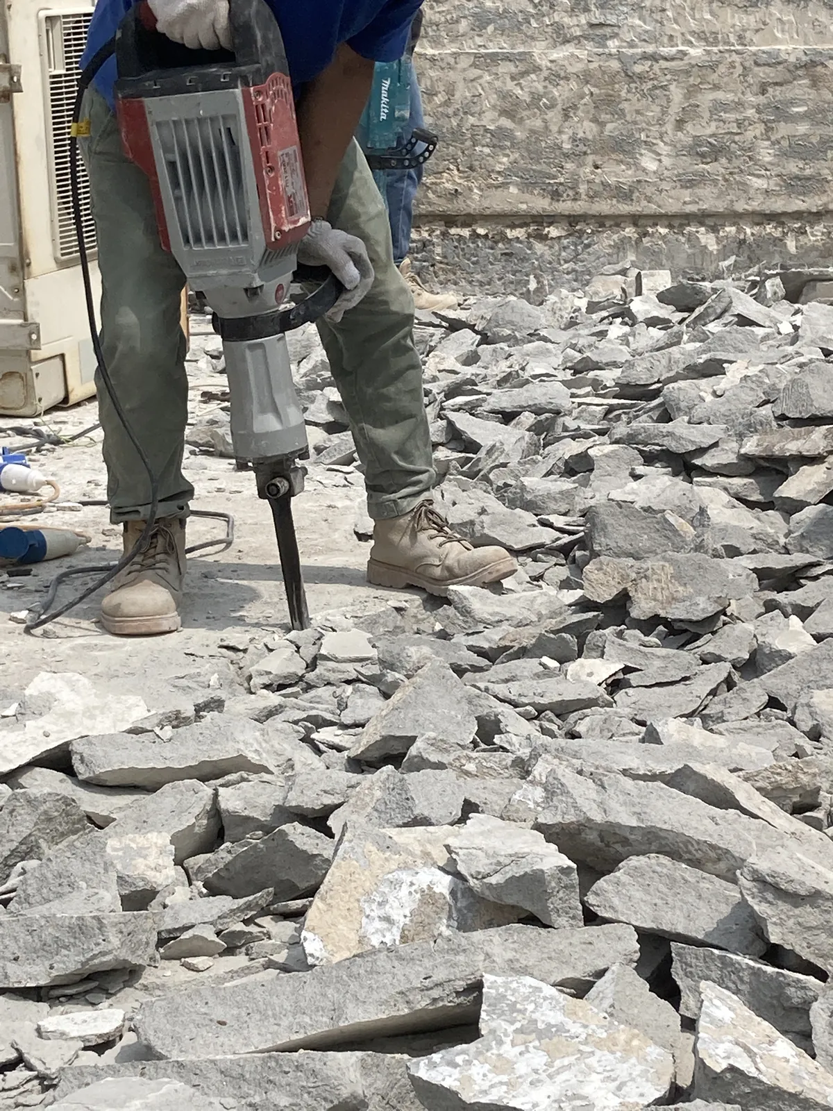 西貢灣景街工人使用電動破碎錘打鑿天台地面,周圍堆有碎塊