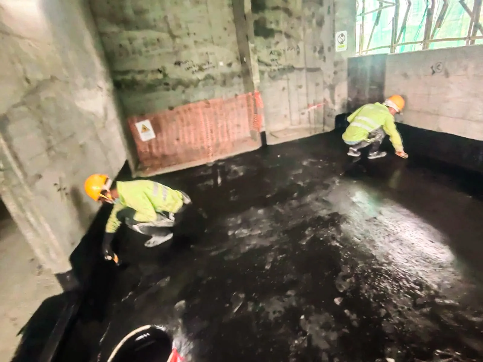 屯門上嵐兩名工人在未飾面樓內空間鋪設黑色地面及牆腳表面