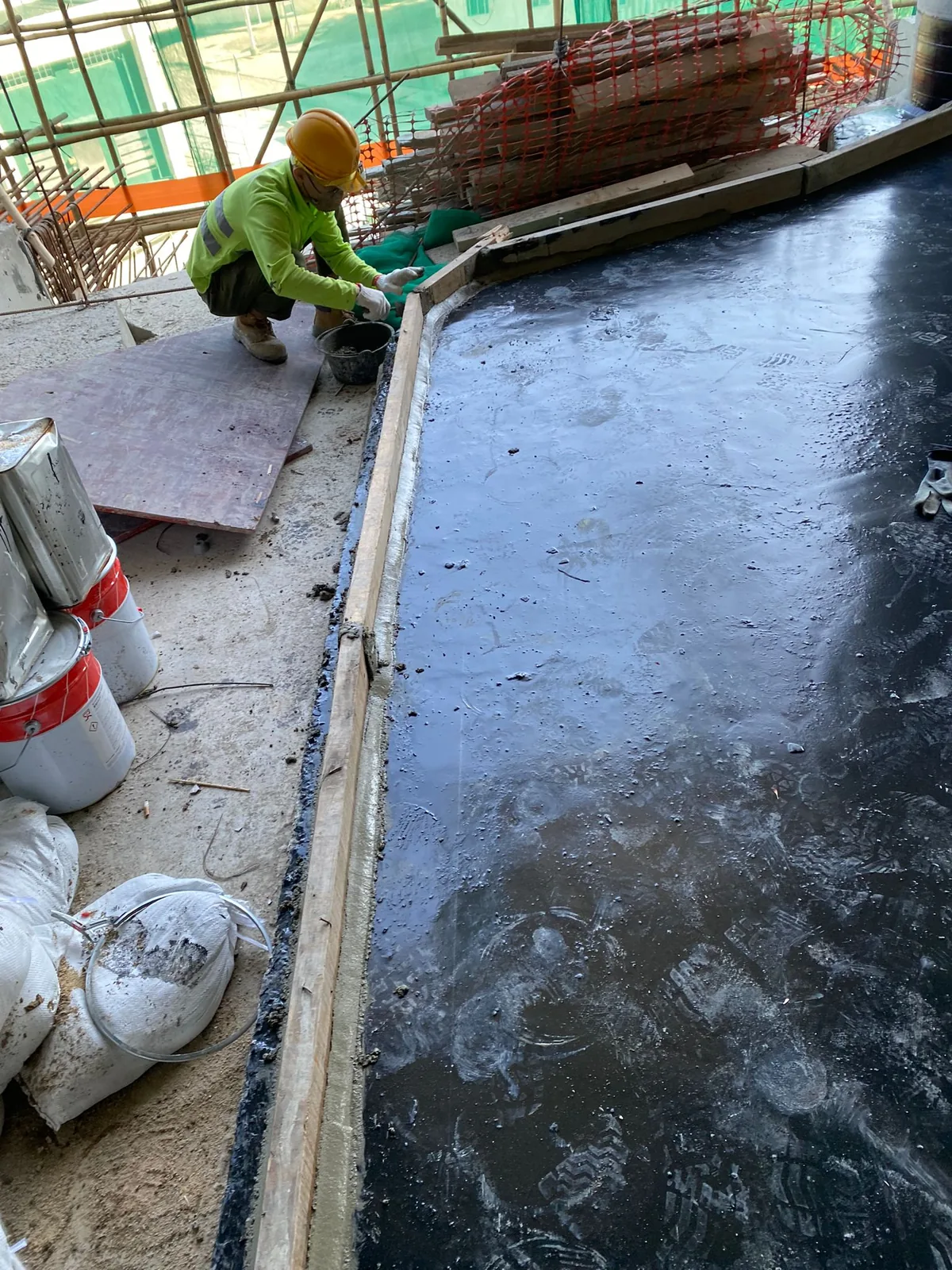 屯門上嵐工人以手工具處理黑色地面層邊位，旁邊可見施工桶具