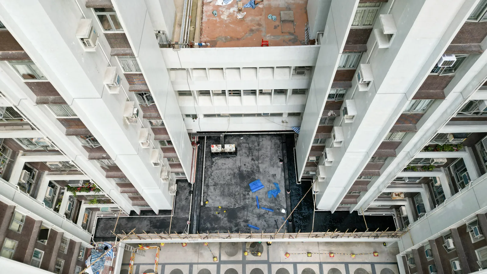 高處俯瞰太古城中心住宅樓間的狹長平台，地面有深色區域及藍色覆蓋物