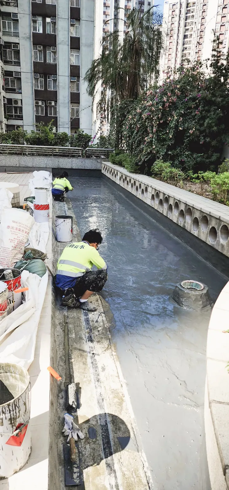 太古城中心兩名工人在花槽旁的狹長平台塗刷灰色表面