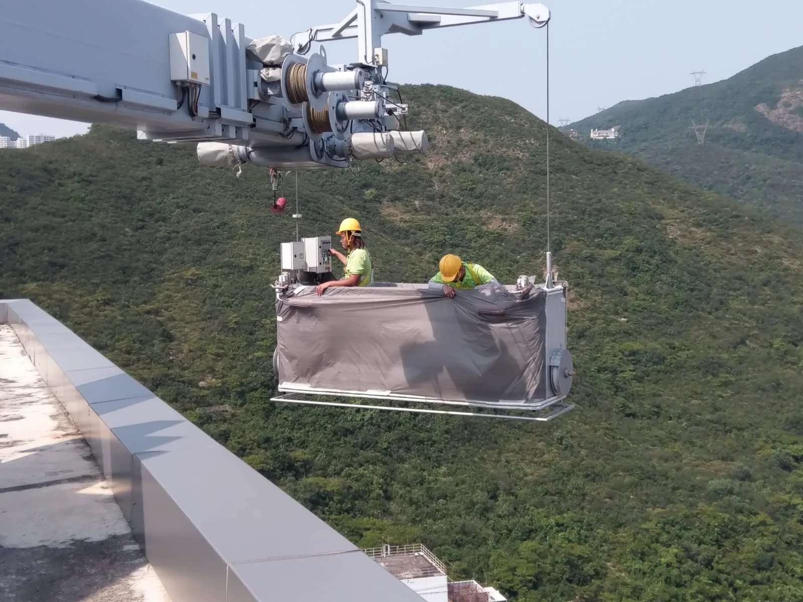 黃竹坑嘉尚匯吊船懸於高層外牆外，兩名工人在平台上作業，背景為山坡