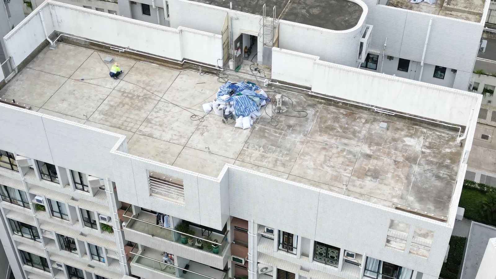 高處俯瞰華翠園住宅天台，斑駁屋面上可見一名工人及覆蓋物料