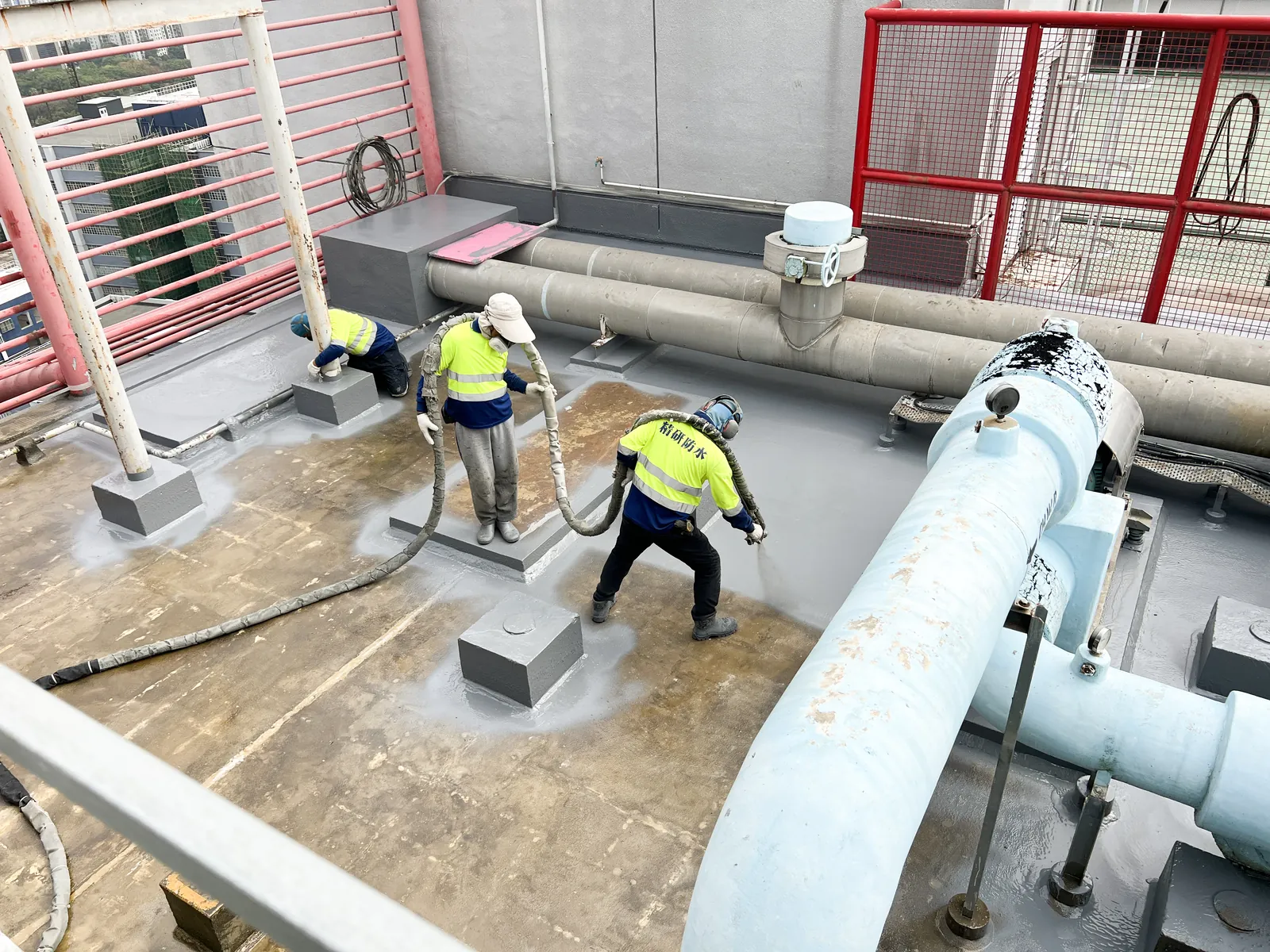 屯門吉田大廈三名工人在大型管道及設備基座旁處理灰色屋面